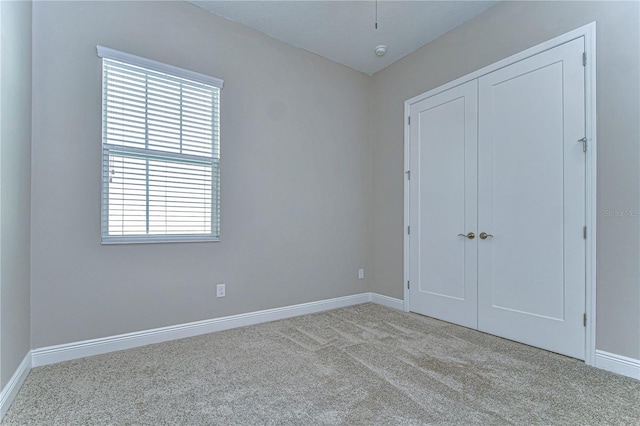 unfurnished bedroom with light colored carpet and a closet