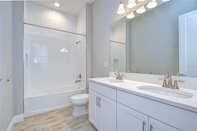 full bathroom with tiled shower / bath combo, vanity, hardwood / wood-style floors, and toilet