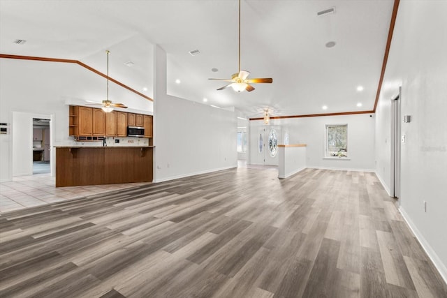 unfurnished living room with crown molding, light hardwood / wood-style flooring, high vaulted ceiling, and ceiling fan