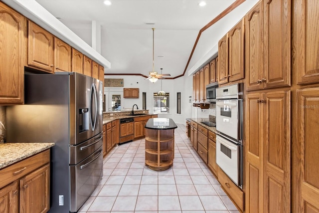 kitchen with light tile patterned flooring, sink, vaulted ceiling, stainless steel appliances, and light stone countertops