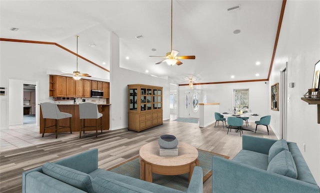 living room featuring high vaulted ceiling, ornamental molding, light hardwood / wood-style floors, and ceiling fan