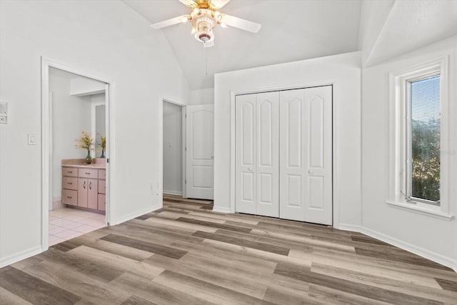 unfurnished bedroom with connected bathroom, high vaulted ceiling, ceiling fan, light hardwood / wood-style floors, and a closet