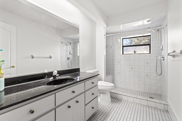 bathroom featuring vanity, tile patterned flooring, toilet, and a tile shower