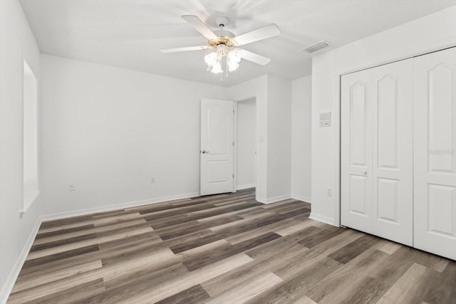 unfurnished bedroom featuring ceiling fan, dark hardwood / wood-style flooring, and a closet