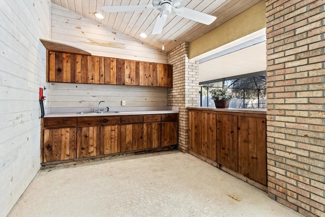 kitchen with sink, wood ceiling, ceiling fan, wooden walls, and vaulted ceiling