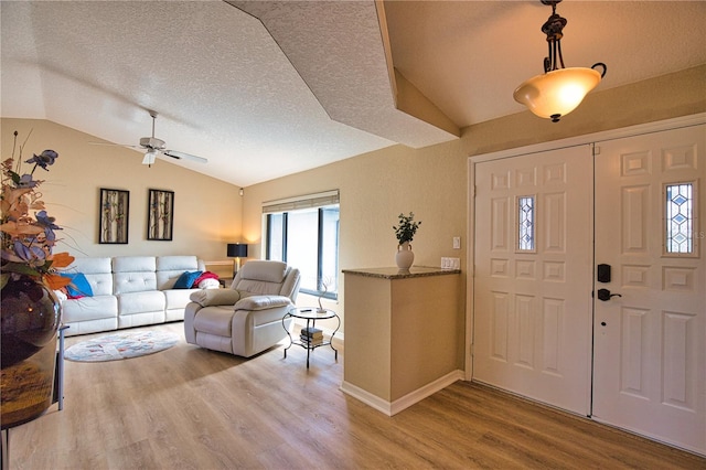 entryway featuring ceiling fan, lofted ceiling, a textured ceiling, and light wood-type flooring