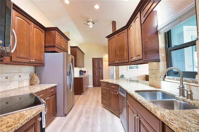 kitchen featuring sink, stainless steel appliances, light stone countertops, vaulted ceiling, and light wood-type flooring