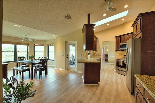 kitchen featuring sink, light hardwood / wood-style flooring, lofted ceiling with skylight, and appliances with stainless steel finishes