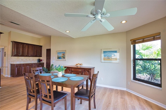 dining area with ceiling fan, lofted ceiling, a textured ceiling, and light hardwood / wood-style flooring