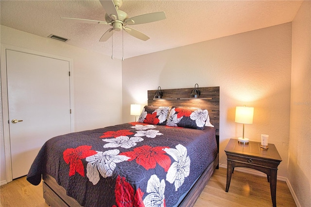 bedroom with ceiling fan, a textured ceiling, and light wood-type flooring