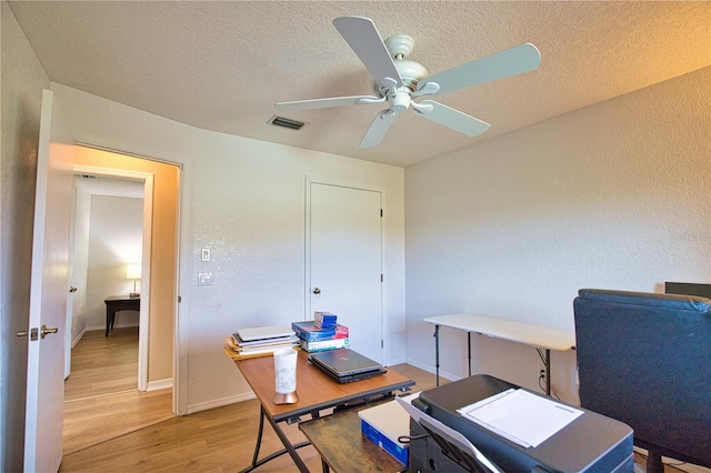 office featuring a textured ceiling, ceiling fan, and light hardwood / wood-style flooring