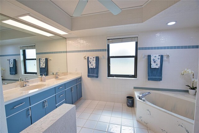 bathroom featuring ceiling fan, tile walls, vanity, tile patterned floors, and a tub