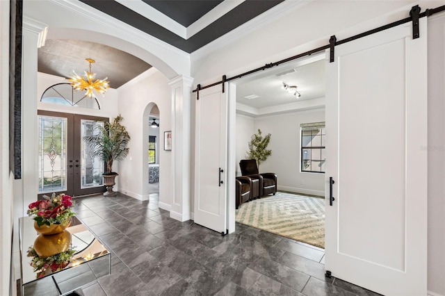 entryway featuring crown molding, plenty of natural light, a barn door, and french doors