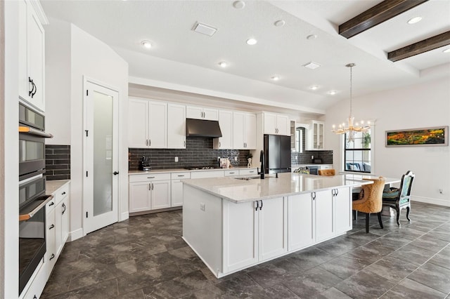 kitchen with white cabinetry, a center island with sink, and stainless steel refrigerator