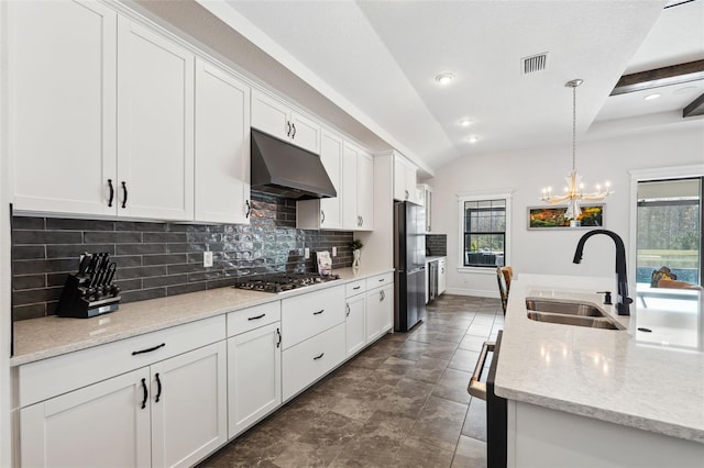 kitchen with appliances with stainless steel finishes, pendant lighting, white cabinetry, sink, and light stone counters