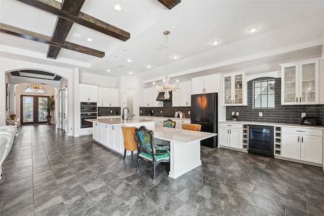 kitchen featuring hanging light fixtures, wine cooler, black appliances, an island with sink, and french doors