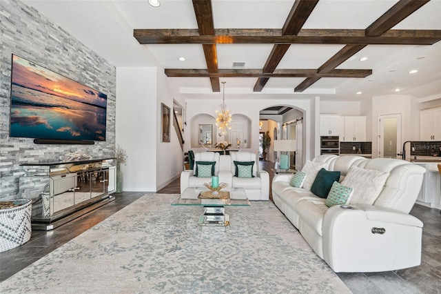 living room with beamed ceiling, coffered ceiling, sink, and a notable chandelier