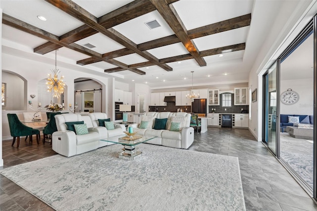 living room with beamed ceiling, coffered ceiling, beverage cooler, and an inviting chandelier