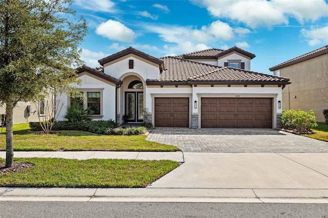 mediterranean / spanish house with a garage and a front lawn