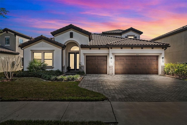 mediterranean / spanish-style house featuring a garage and a yard