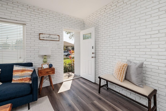 entrance foyer featuring a healthy amount of sunlight, brick wall, and dark wood-type flooring