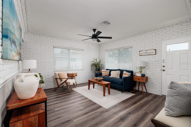 living room with ceiling fan, brick wall, and dark hardwood / wood-style flooring