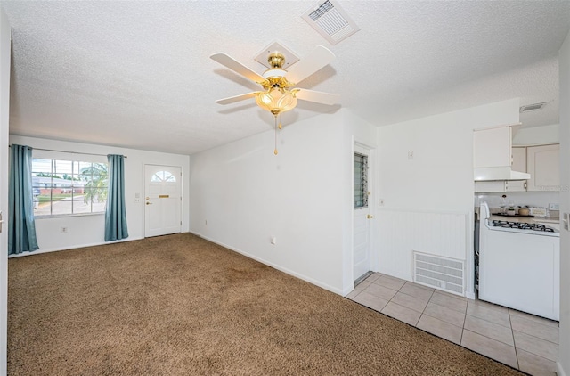 unfurnished living room featuring ceiling fan, light carpet, and a textured ceiling