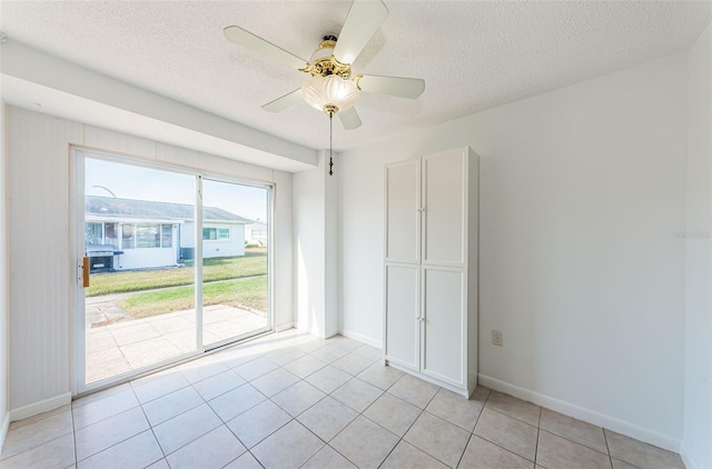 tiled empty room with ceiling fan and a textured ceiling