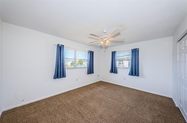 empty room with ceiling fan, carpet floors, and a textured ceiling