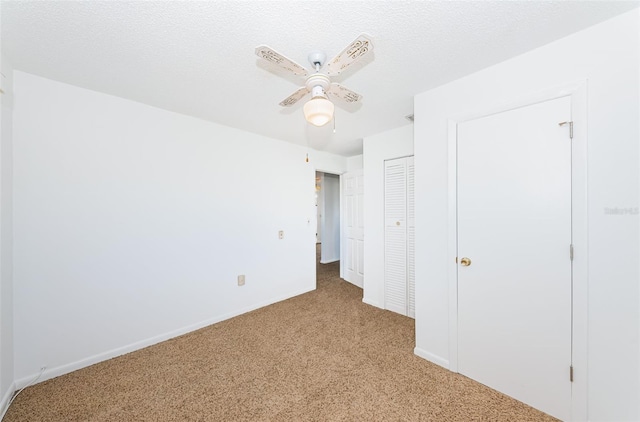 unfurnished bedroom with ceiling fan, light colored carpet, and a textured ceiling