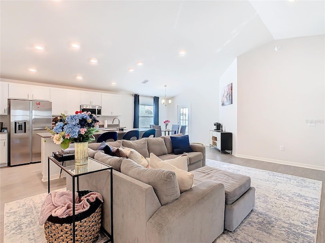 living room with light wood finished floors, baseboards, an inviting chandelier, vaulted ceiling, and recessed lighting