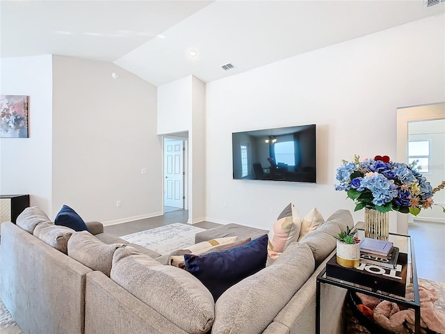 living room with visible vents, vaulted ceiling, baseboards, and wood finished floors