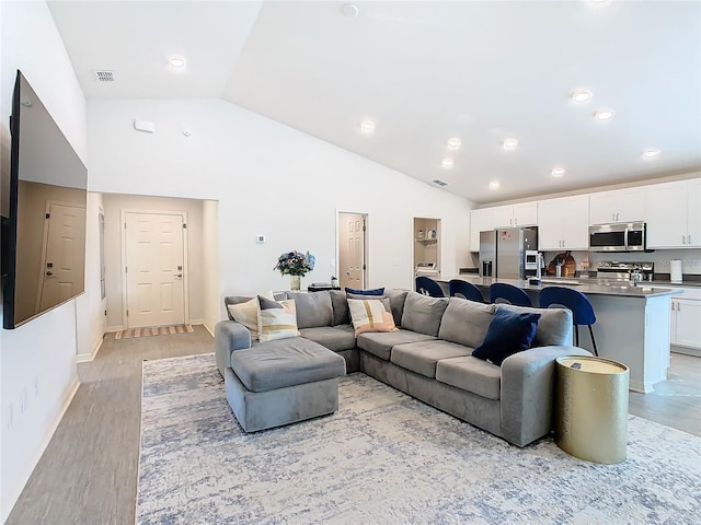 living room featuring recessed lighting, visible vents, light wood-style floors, high vaulted ceiling, and baseboards