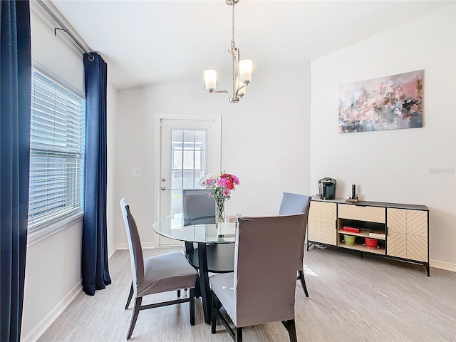 dining area with a wealth of natural light, baseboards, a notable chandelier, and light wood finished floors