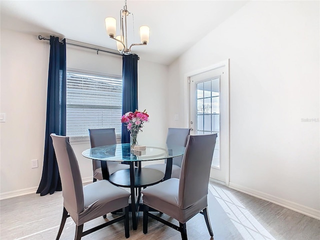 dining space with baseboards, light wood-type flooring, and a notable chandelier