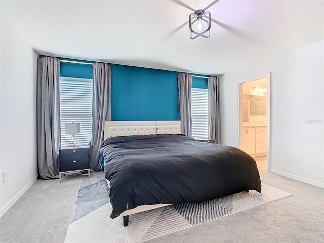 carpeted bedroom featuring ensuite bathroom and baseboards