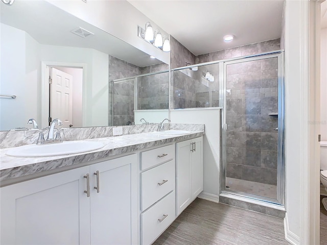 full bathroom with double vanity, a stall shower, toilet, and a sink