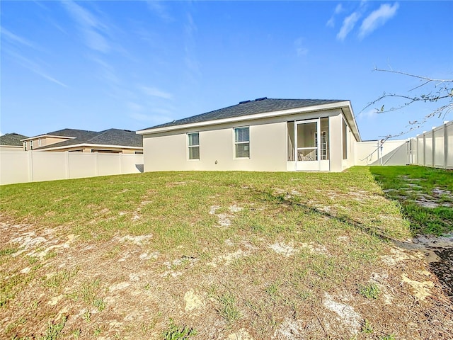 rear view of house featuring a yard, a fenced backyard, and stucco siding