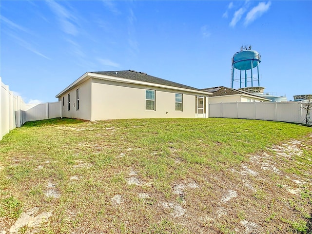 back of house featuring a fenced backyard, a lawn, and stucco siding