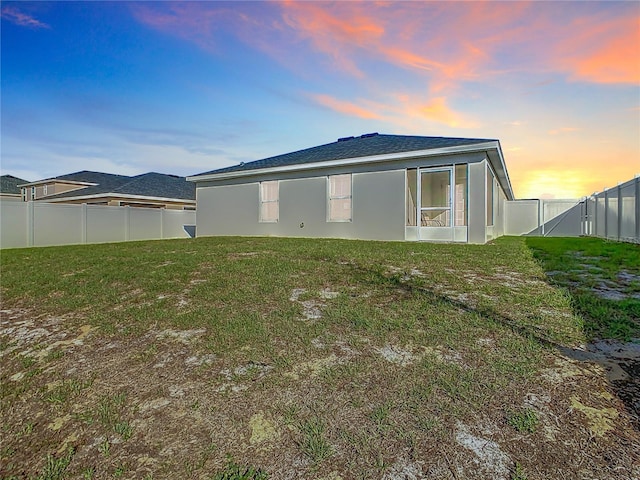 back of property with a yard, a fenced backyard, and stucco siding