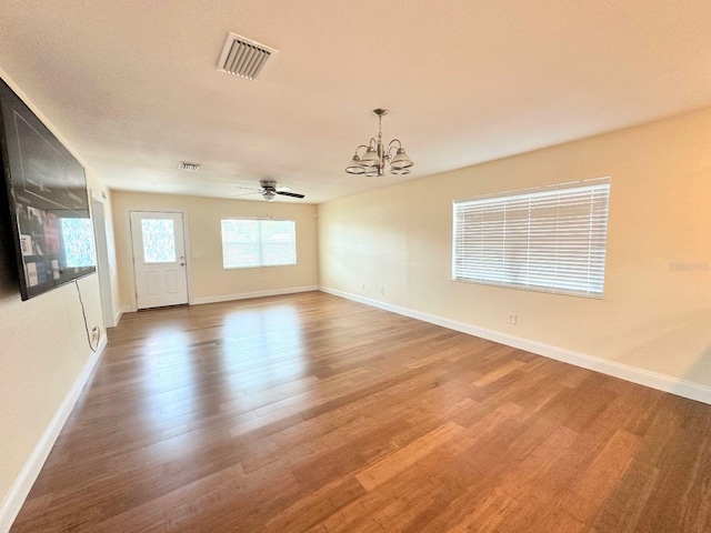 spare room featuring hardwood / wood-style flooring and ceiling fan with notable chandelier