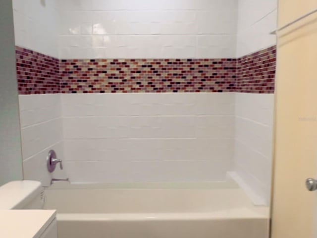 full bathroom featuring tiled shower / bath combo, vanity, and toilet