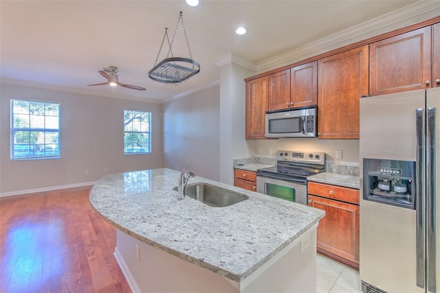 kitchen with sink, ornamental molding, a kitchen island with sink, light stone counters, and stainless steel appliances