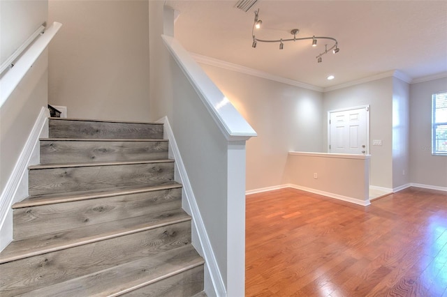 staircase featuring ornamental molding, wood-type flooring, and track lighting