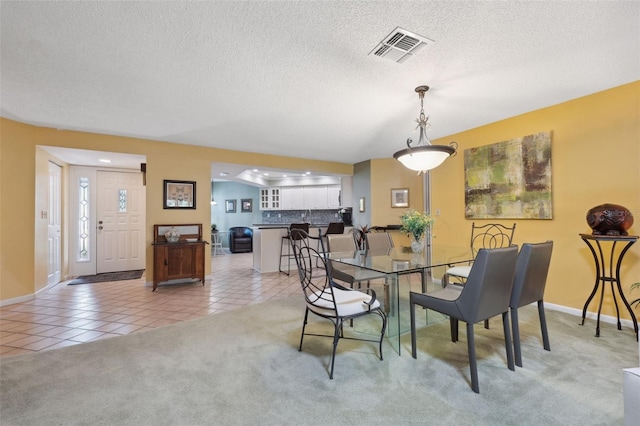 dining area with light carpet and a textured ceiling