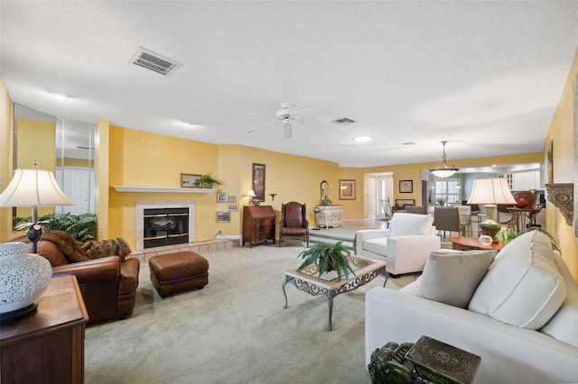 carpeted living room with a tile fireplace and ceiling fan