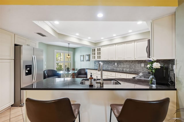 kitchen with sink, appliances with stainless steel finishes, a tray ceiling, a kitchen bar, and kitchen peninsula