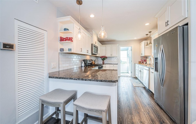 kitchen featuring stainless steel appliances, hanging light fixtures, white cabinets, and kitchen peninsula