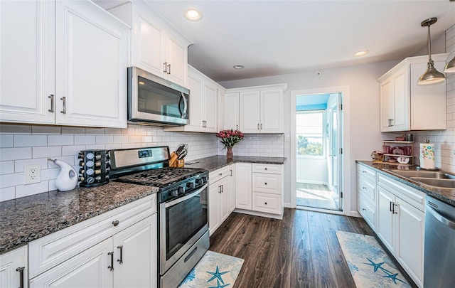 kitchen featuring hanging light fixtures, dark wood-type flooring, white cabinets, and appliances with stainless steel finishes