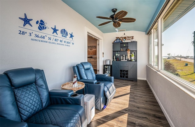 living area featuring dark wood-type flooring, ceiling fan, and bar area